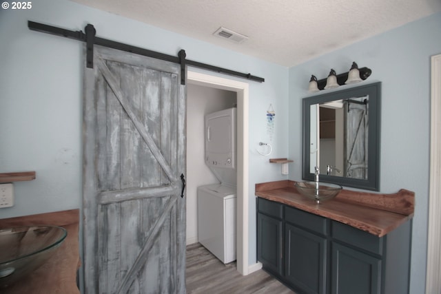 1974 N Laurelwood St, Canby, OR 97013 - bathroom featuring stacked washer and clothes dryer, vanity, wood finished floors, and a textured ceiling