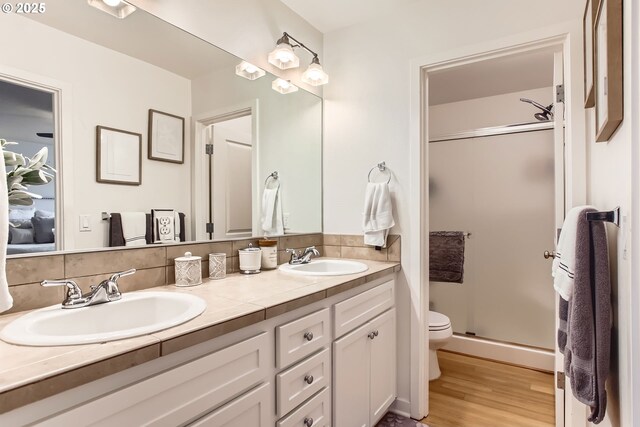 bathroom with backsplash, vanity, a shower with door, wood-type flooring, and toilet