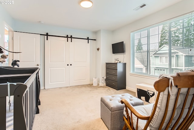 bedroom with multiple windows, a barn door, light colored carpet, and a closet