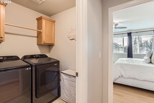 clothes washing area with cabinets, light wood-type flooring, washer and clothes dryer, and ceiling fan