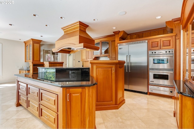 kitchen with island exhaust hood, a center island, a warming drawer, brown cabinets, and appliances with stainless steel finishes
