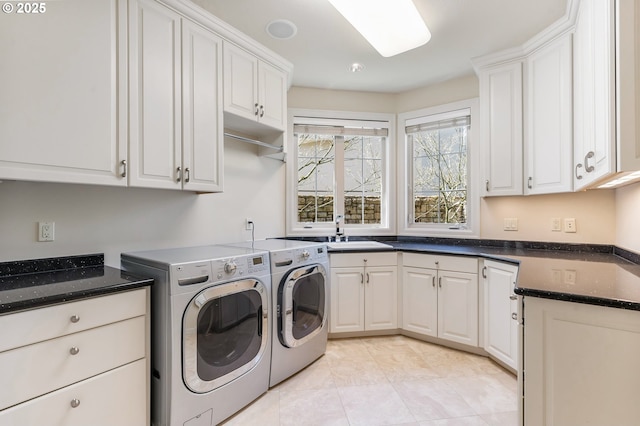 washroom featuring cabinet space, light tile patterned floors, washer and clothes dryer, and a sink