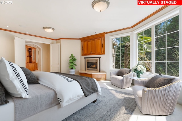 bedroom with a glass covered fireplace and ornamental molding