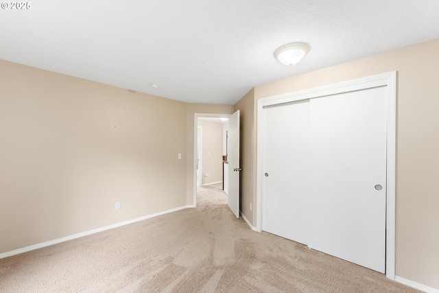 unfurnished bedroom with a closet, baseboards, and light colored carpet