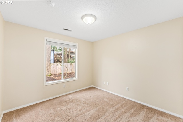 spare room featuring carpet flooring, baseboards, and visible vents