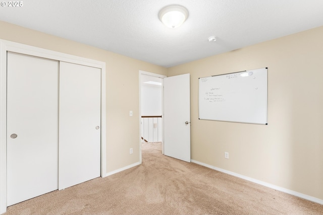 unfurnished bedroom with carpet flooring, baseboards, and a closet