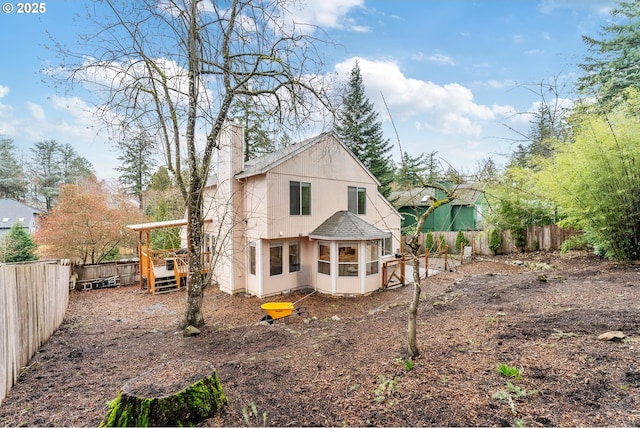 rear view of property with stucco siding, a fenced backyard, and a chimney