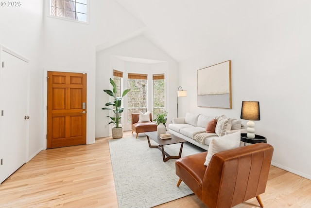 living area featuring light wood-type flooring and high vaulted ceiling