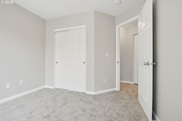 unfurnished bedroom featuring carpet flooring, baseboards, and a closet