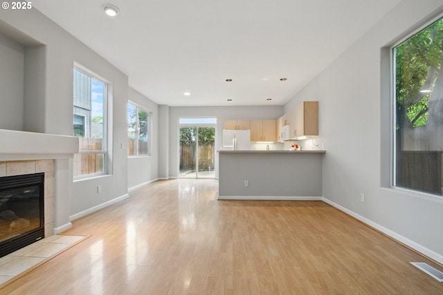 unfurnished living room featuring light wood-style floors, baseboards, a fireplace, and recessed lighting