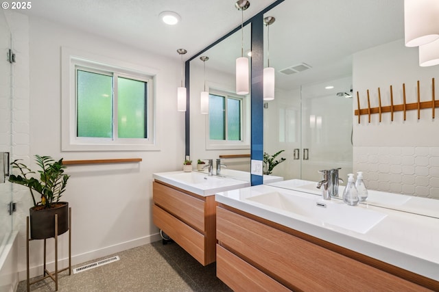 full bathroom with baseboards, two vanities, a shower with shower door, and visible vents