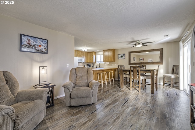 living room with a textured ceiling, ceiling fan, dark hardwood / wood-style floors, and a healthy amount of sunlight