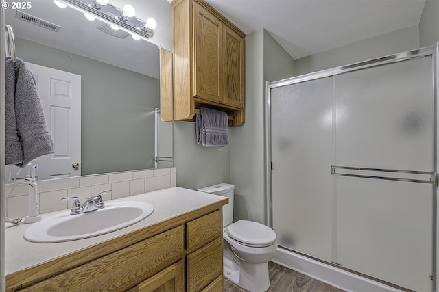 bathroom featuring an enclosed shower, tasteful backsplash, vanity, and toilet