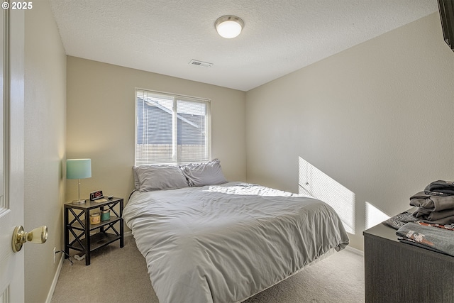 bedroom with a textured ceiling and light colored carpet