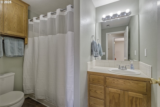 bathroom featuring toilet, vanity, and curtained shower