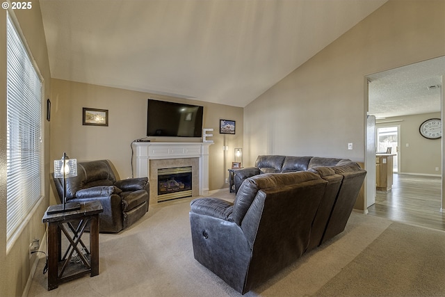 carpeted living room with a tile fireplace and vaulted ceiling