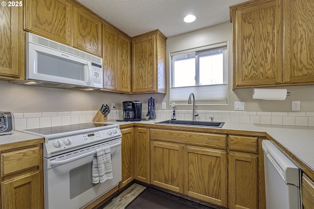 kitchen featuring sink, white appliances, and a textured ceiling