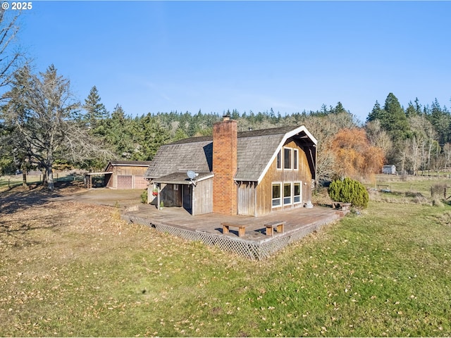 rear view of property featuring a yard and an outbuilding