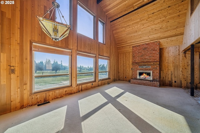 unfurnished living room featuring carpet floors, a fireplace, wood ceiling, and wooden walls