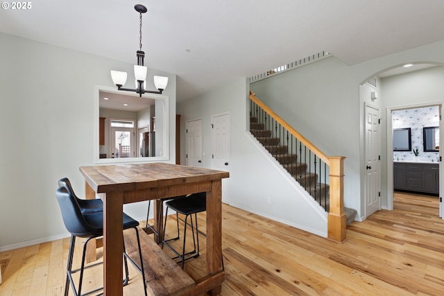 dining space featuring stairs, baseboards, arched walkways, light wood-style floors, and recessed lighting