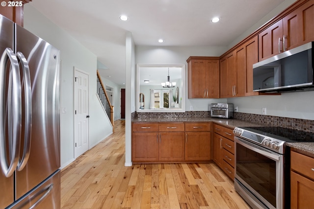 kitchen featuring an inviting chandelier, brown cabinets, stainless steel appliances, light wood-type flooring, and recessed lighting