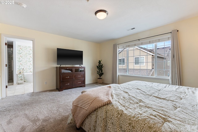 bedroom featuring carpet, ensuite bathroom, visible vents, and baseboards