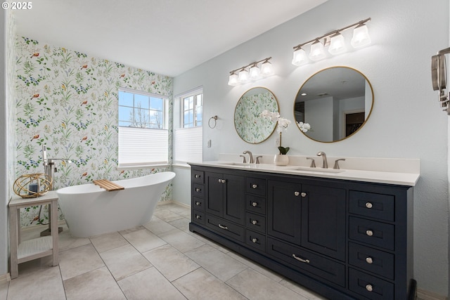 full bathroom featuring a freestanding tub, wallpapered walls, a sink, and double vanity