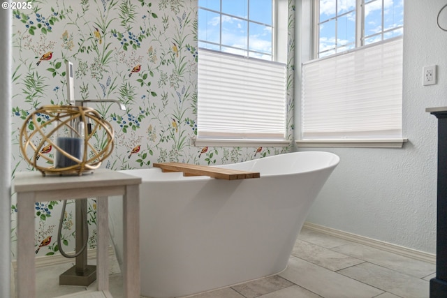 bathroom featuring a freestanding bath and baseboards