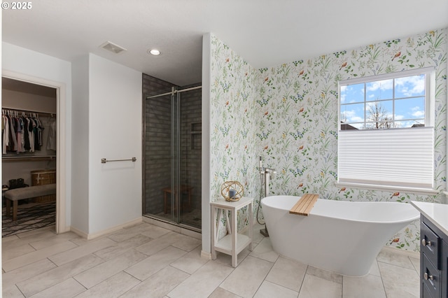 bathroom with a stall shower, wallpapered walls, visible vents, a freestanding bath, and a spacious closet