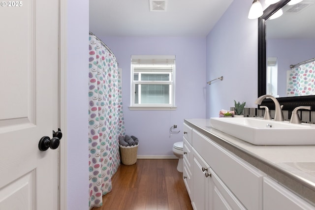 bathroom featuring toilet, visible vents, wood finished floors, and vanity
