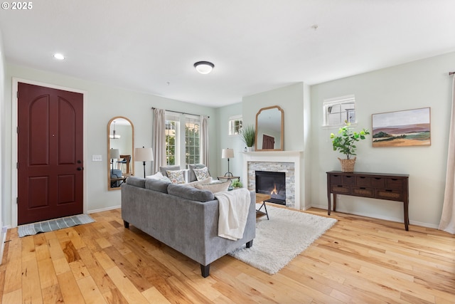 living area featuring a fireplace, light wood finished floors, baseboards, and recessed lighting