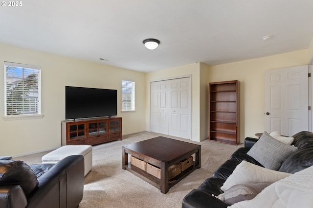living area with light colored carpet, visible vents, and baseboards