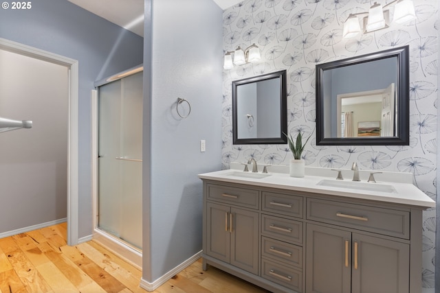 bathroom with a sink, baseboards, and wallpapered walls