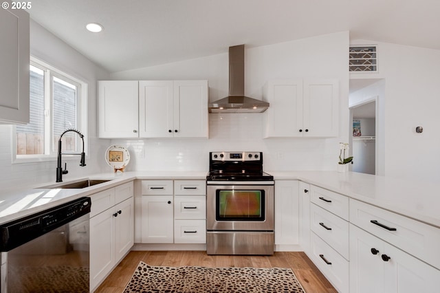 kitchen with a sink, light wood-style floors, vaulted ceiling, appliances with stainless steel finishes, and wall chimney range hood