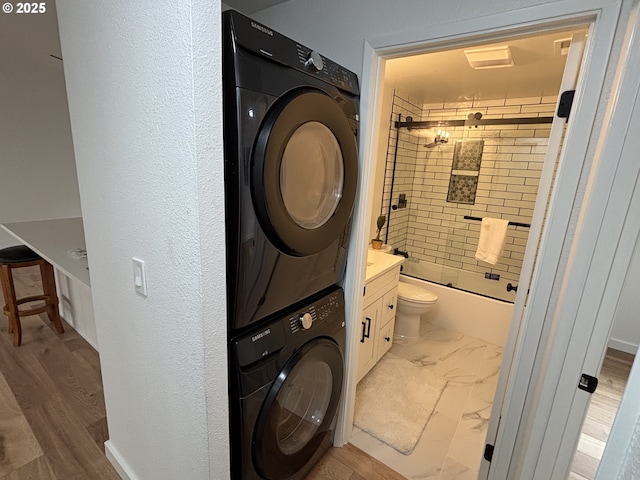 clothes washing area featuring marble finish floor, laundry area, baseboards, and stacked washer / drying machine