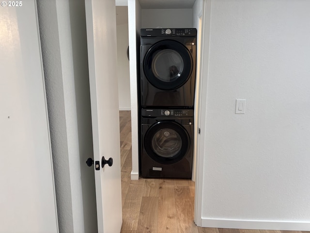 laundry room with light wood-style floors, laundry area, baseboards, and stacked washing maching and dryer