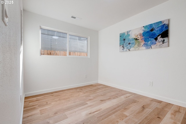 empty room featuring visible vents, baseboards, and wood finished floors