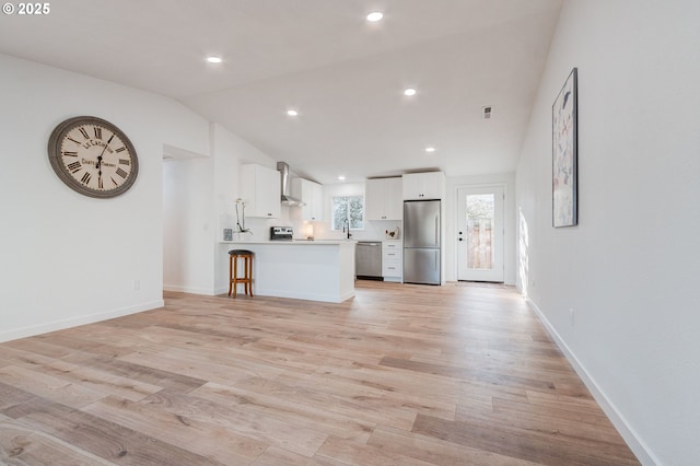 unfurnished living room featuring lofted ceiling, light wood-style floors, and baseboards