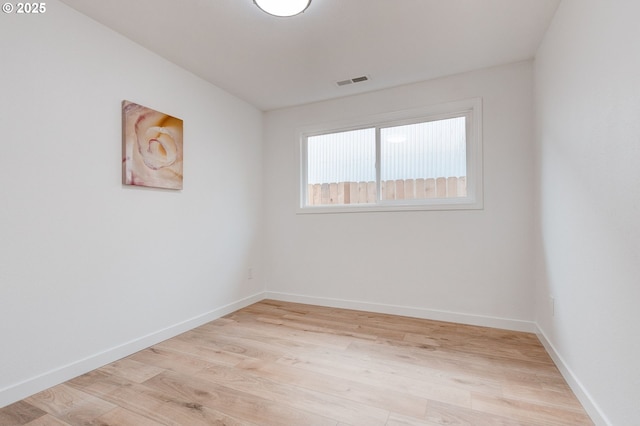 empty room with light wood-style flooring, visible vents, and baseboards