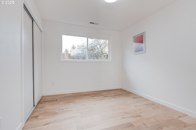 empty room with visible vents, light wood-style flooring, and baseboards