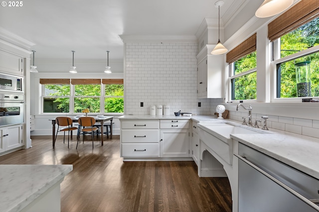 2225 NE 22nd Ave, Portland, OR 97212 - kitchen with appliances with stainless steel finishes, ornamental molding, tasteful backsplash, white cabinets, and dark wood-style floors