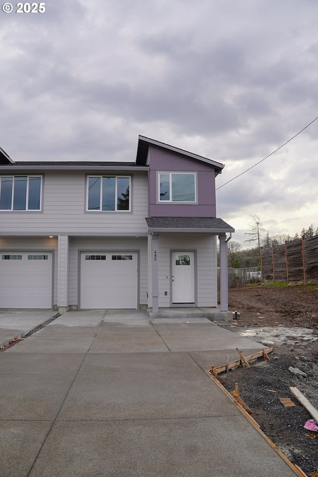 view of property featuring a garage, fence, and concrete driveway