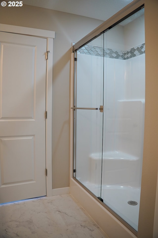 full bath featuring marble finish floor, baseboards, and a shower with shower door