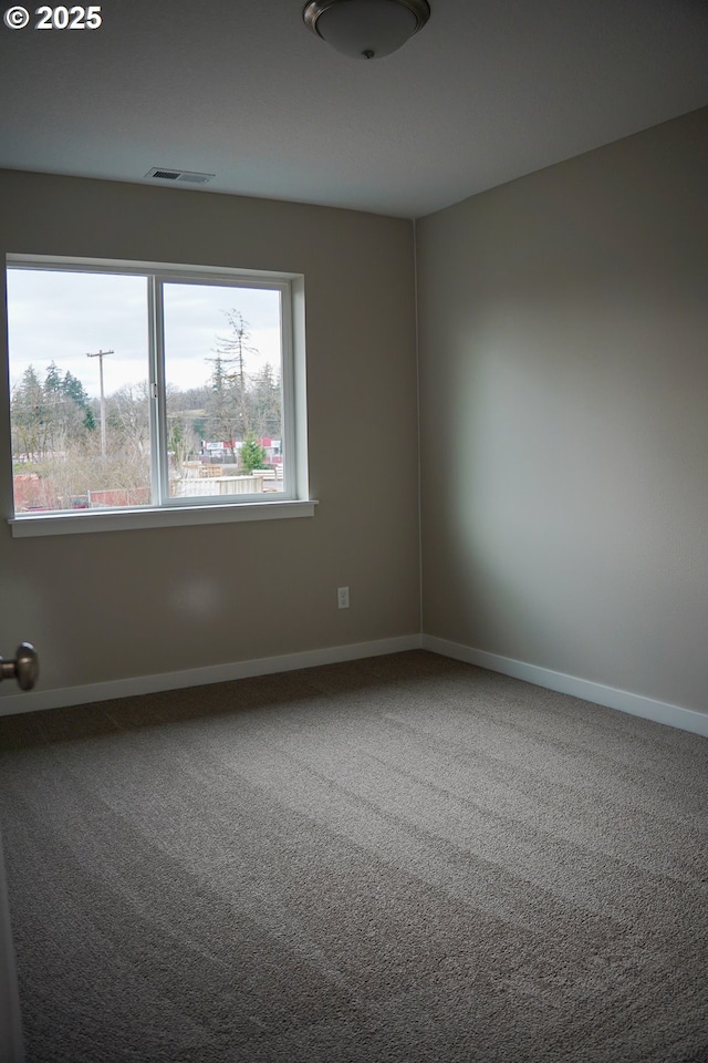 carpeted spare room featuring visible vents and baseboards