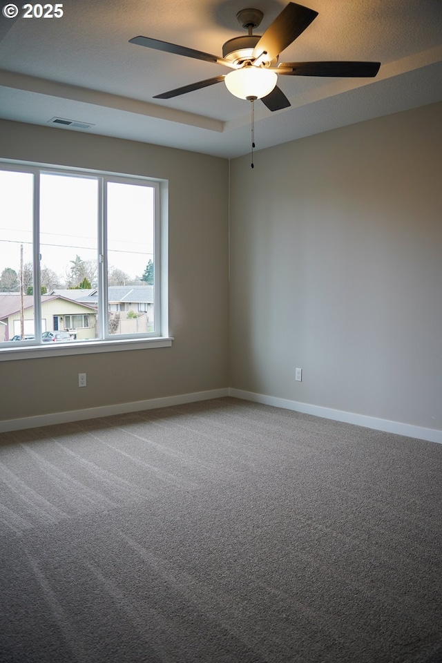 carpeted spare room with ceiling fan, visible vents, and baseboards