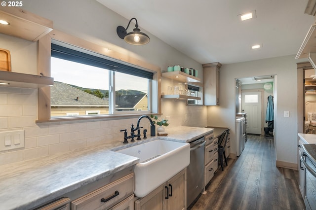 128 NW 20th Ave, Rockaway Beach, OR 97136 - kitchen featuring stainless steel dishwasher, washing machine and clothes dryer, decorative backsplash, a sink, and dark wood-style floors