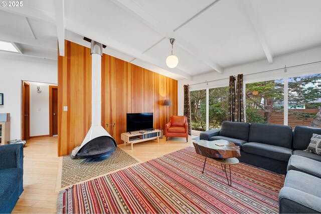 living room with beam ceiling, wooden walls, and light wood-style floors