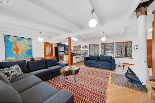 living room featuring light wood finished floors, vaulted ceiling with beams, and decorative columns