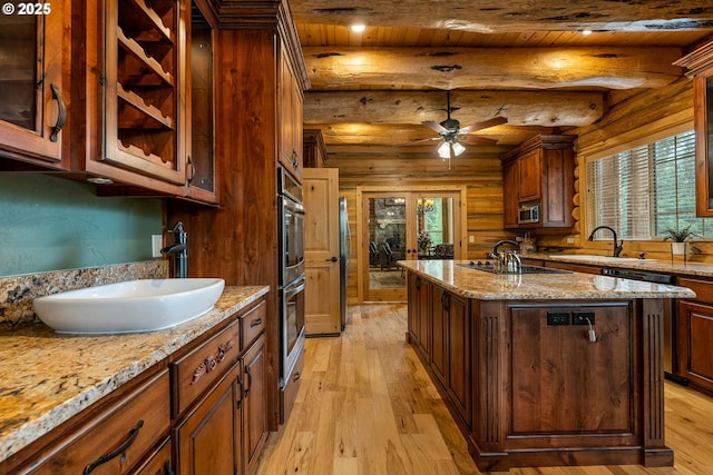 400 Rockinghorse Dr, Grants Pass, OR 97527 - kitchen featuring light wood finished floors, stainless steel appliances, a sink, a kitchen island with sink, and rustic walls