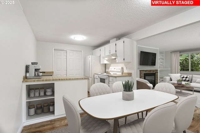 7124 SW Murray Blvd, Beaverton, OR 97008 - dining space with a textured ceiling, dark wood-type flooring, a fireplace, and baseboards